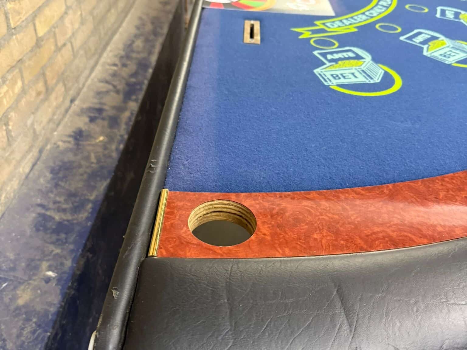 Professionele tweedehands blackjacktafel uit casinoverhuur, blauw speelveld met bedrukt inzetvlak en houten afwerking.