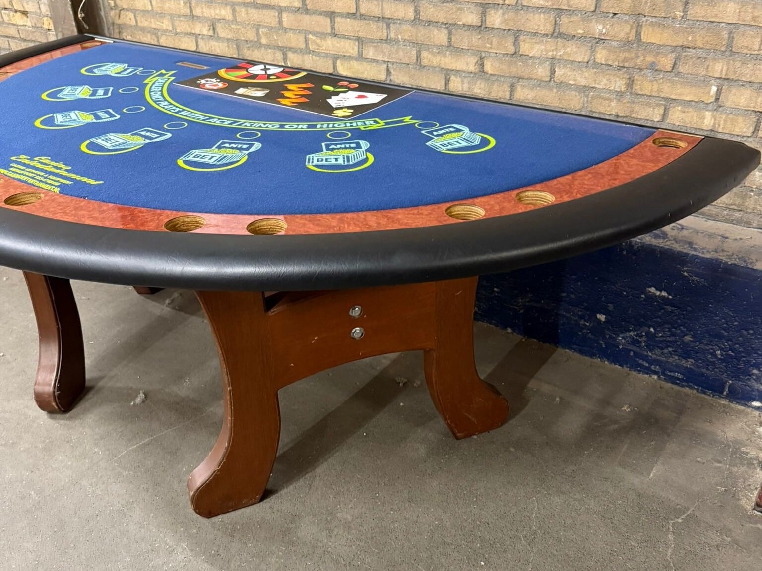 Bovenaanzicht van tweedehands blackjacktafel met zwart leren rand, houten afwerking en blauw speelveld.