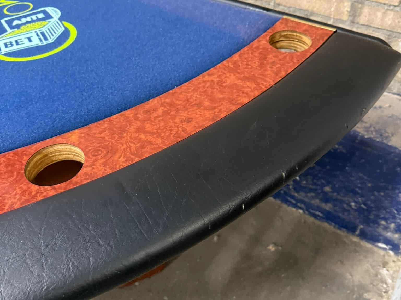Close-up van tweedehands blackjacktafel met zwarte skyleren rand en cupholders.