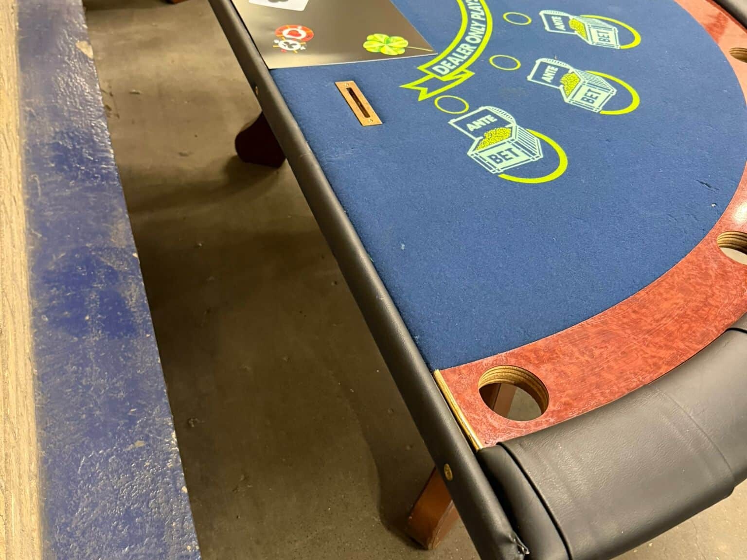 Blackjacktafel uit casinoverhuur met stevig houten onderstel en blauw speelveld, tweedehands maar volledig functioneel.