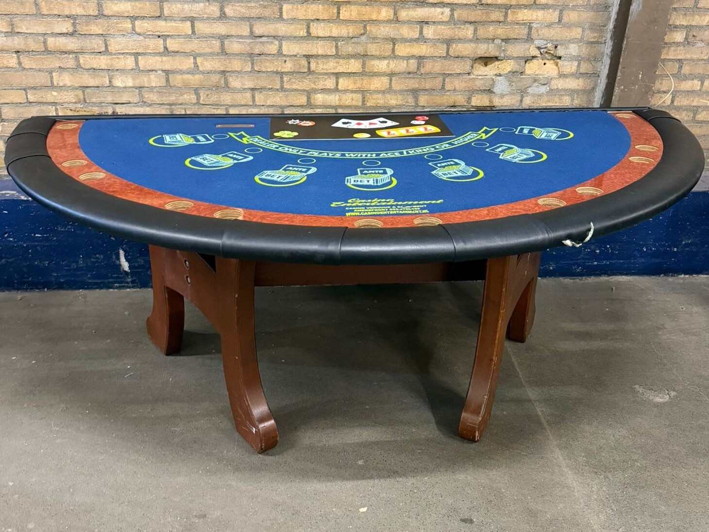 Tweedehands blackjacktafel met houten onderstel en zwart leren rand, blauw speelveld met inzetvakken.