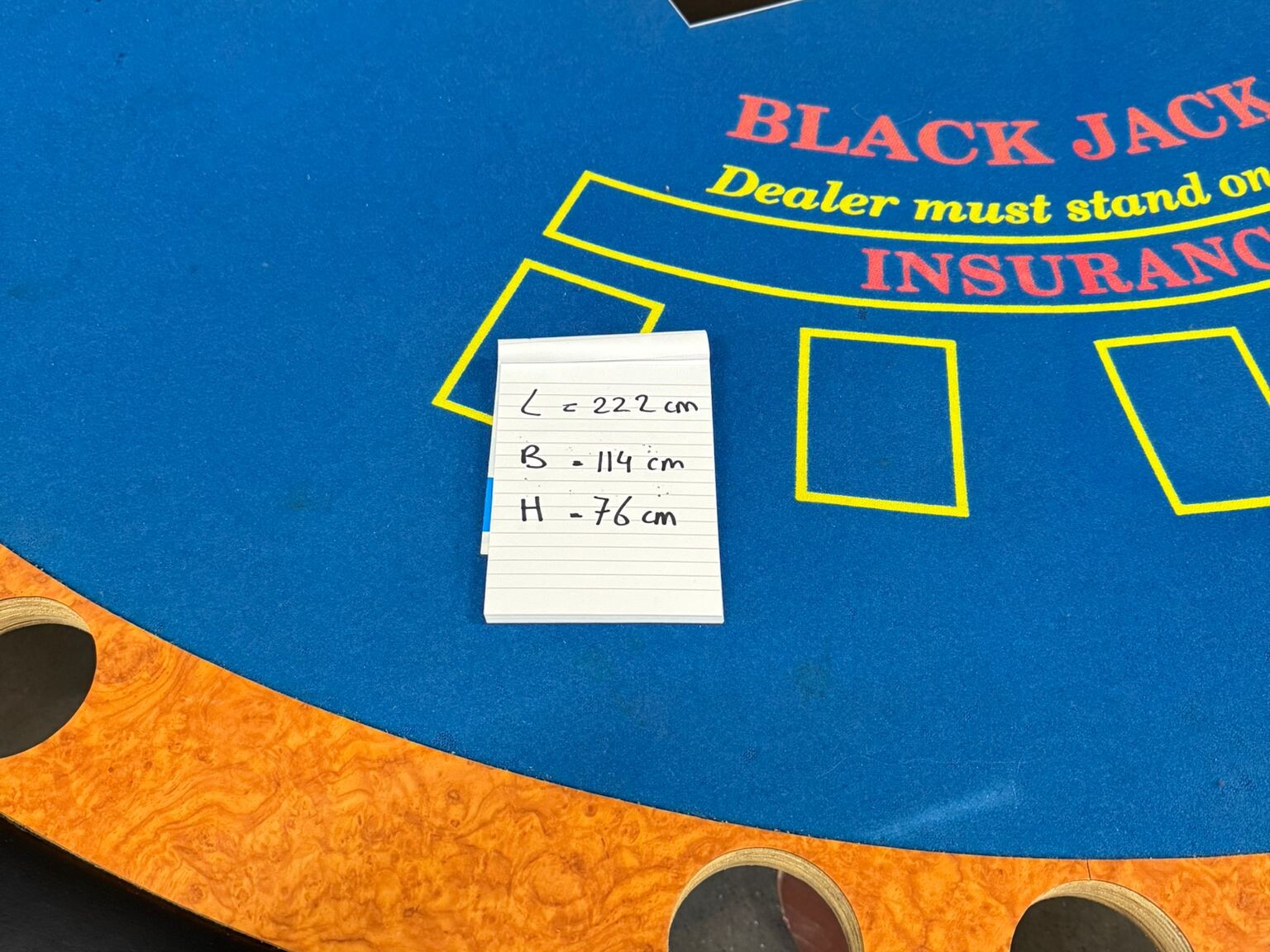 Blauw speelveld van tweedehands blackjacktafel met inzetvakken, cupholders en kleurrijke details.