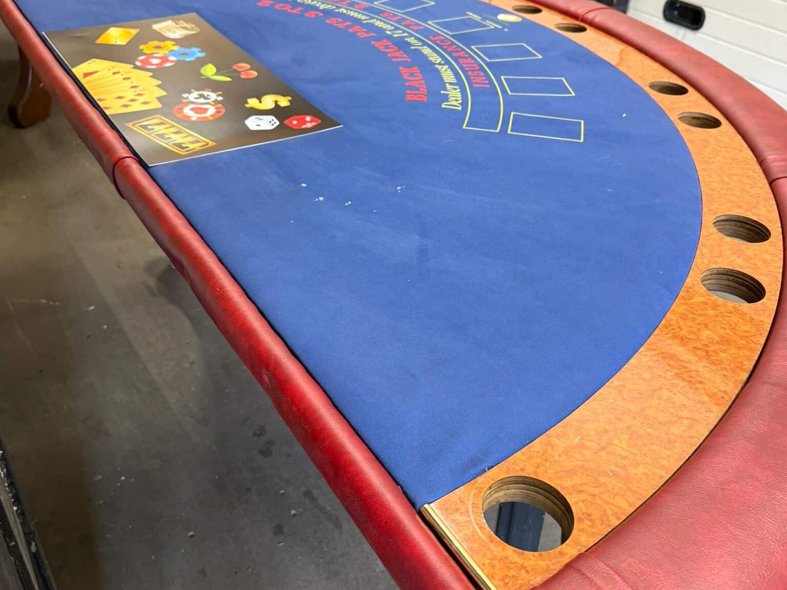 Blauw speelveld van een tweedehands blackjacktafel met kaartvakken en chiptray.