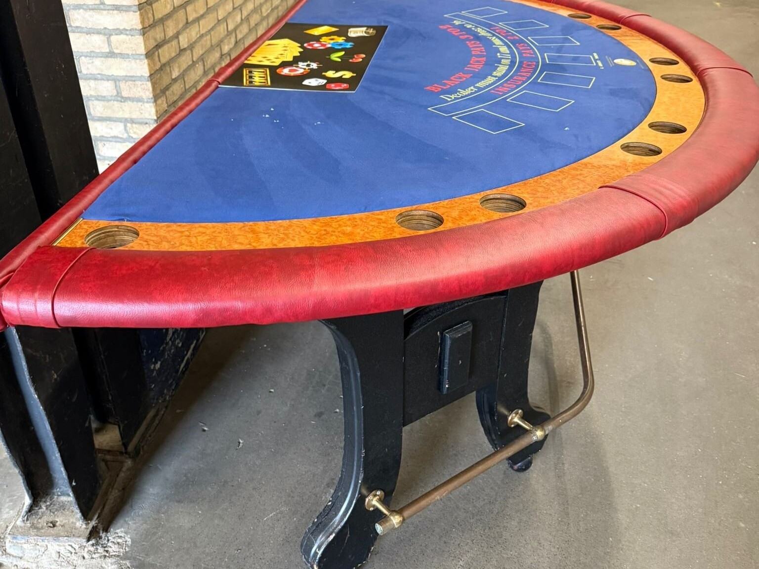 Zijaanzicht van tweedehands blackjacktafel met rode skyleren rand en houten details.